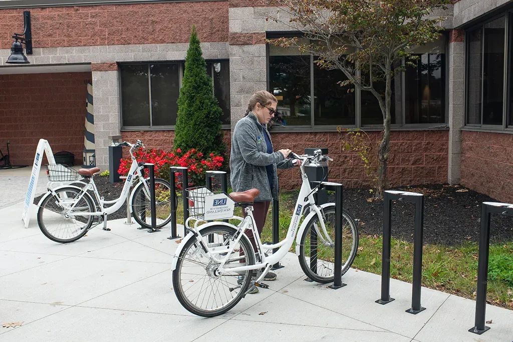 A U N E student getting a bike from the U N E bike share rack