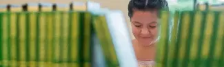 A student is visible behind a row of books